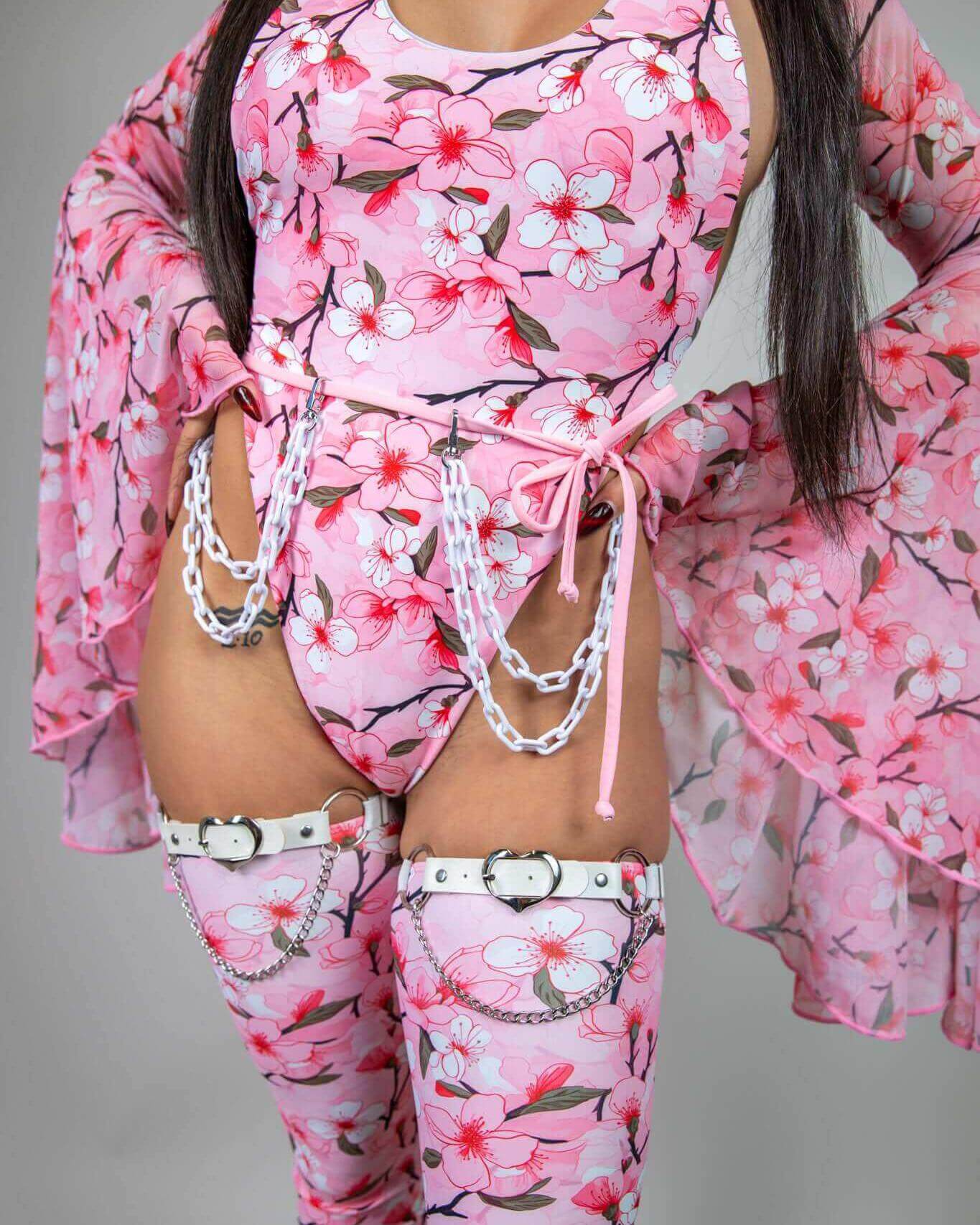 Model showcasing the Sakura Temptation Cheeky One Piece with cherry blossom designs and matching accessories. Perfect for rave outfits.