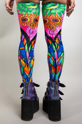 An up close photo of a girl's legs. She is wearing rainbow stained glass printed leg sleeves that go up to her mid thigh.