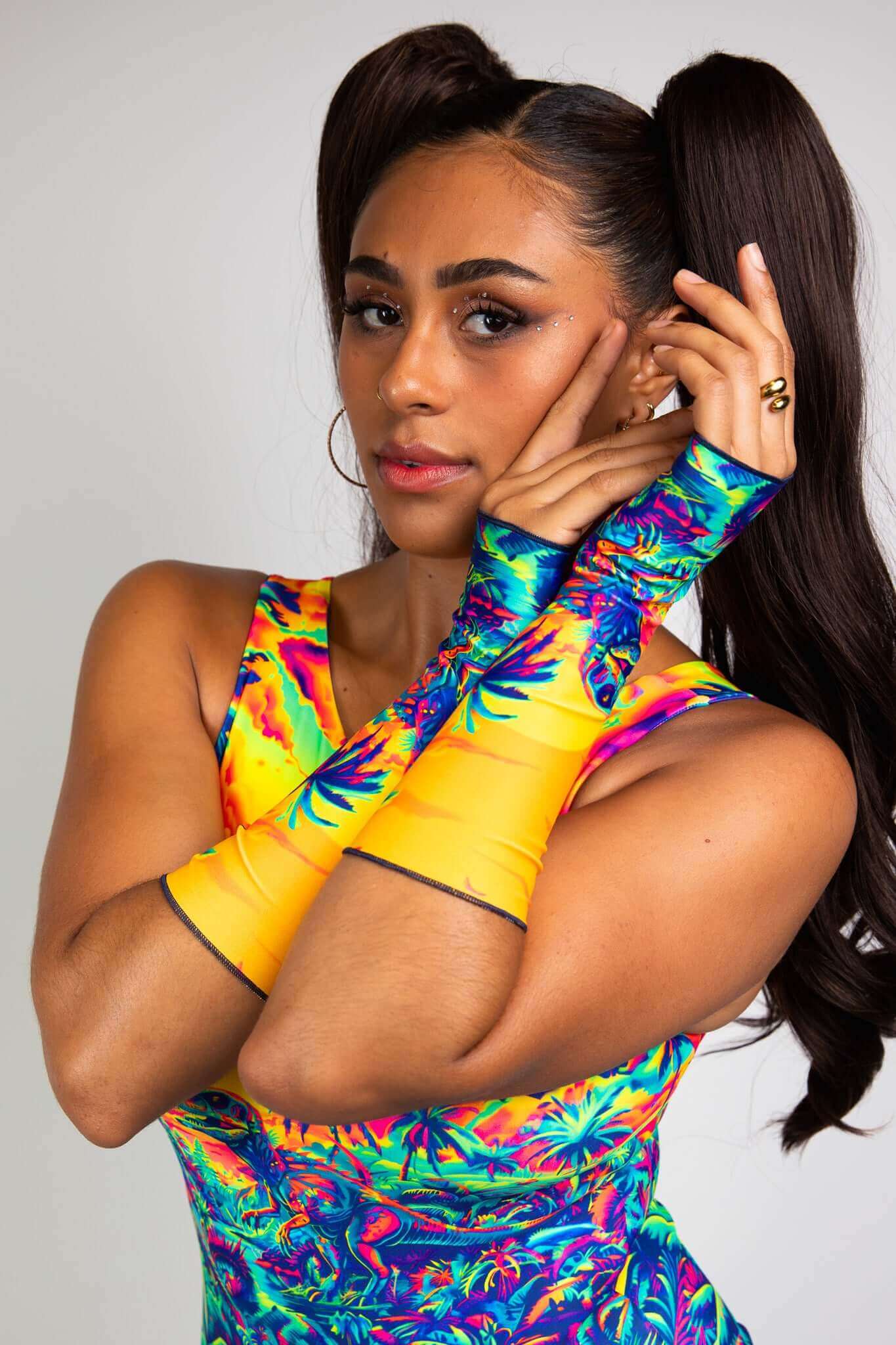 Model showcasing a vibrant dinosaur print rave bodysuit with matching arm sleeves, designed by Freedom Rave Wear.