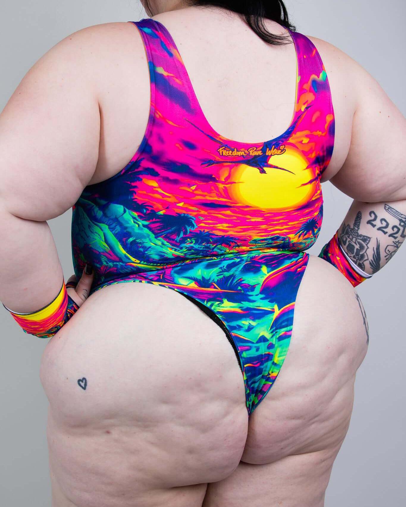 Colorful back view of aplus-size model in a vibrant sunset-themed swimsuit, showcasing bold patterns and style.