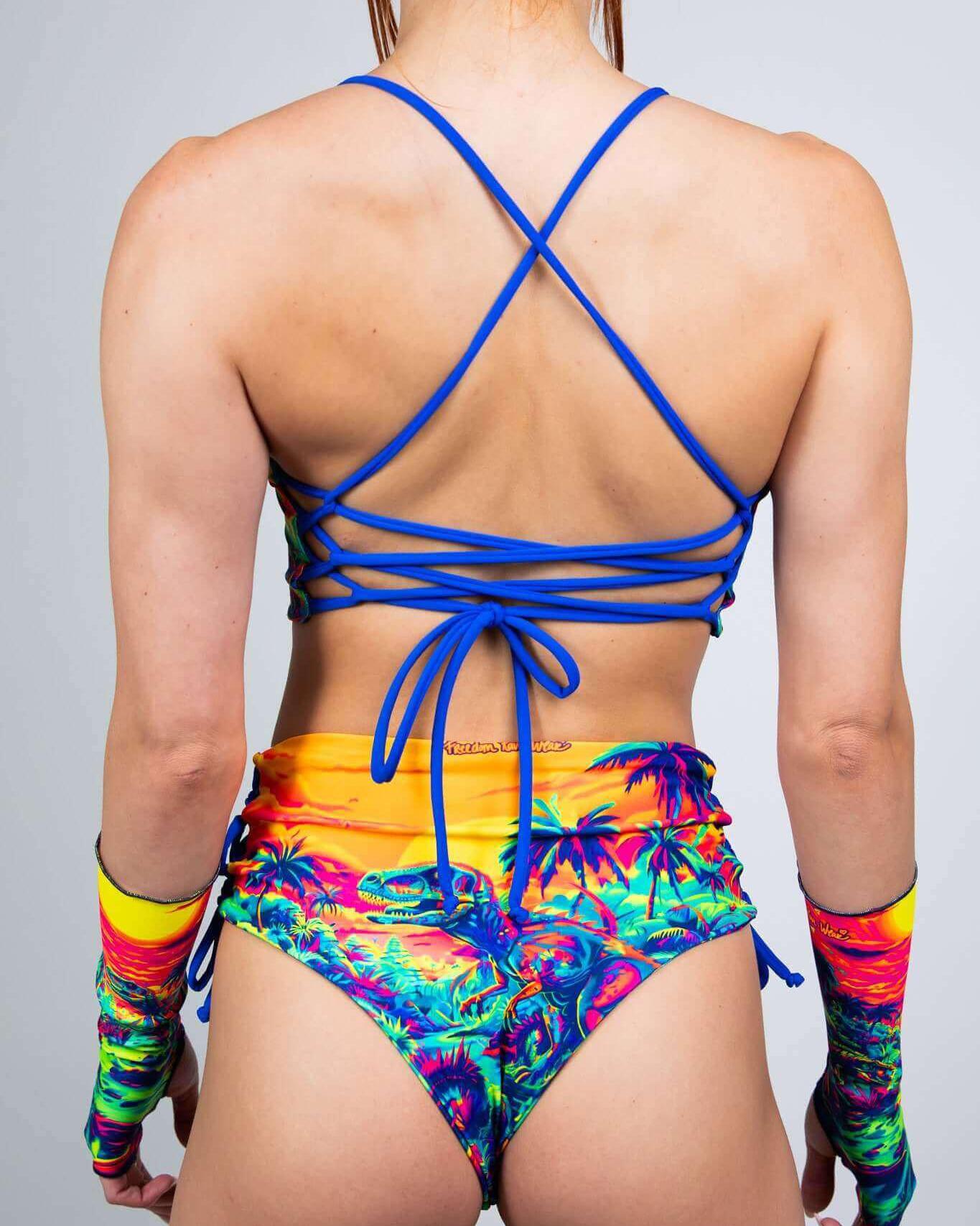 Back view of a model in a colorful Saurian swimsuit with adjustable tie straps and matching arm sleeves, perfect for rave outfits.