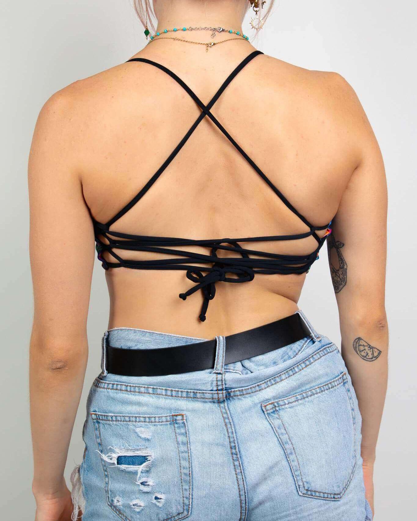 Back view of a model wearing the Saurian Reversible Lush Top with crisscross straps, paired with high-waisted denim shorts.