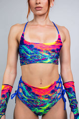 Model wearing a vibrant multicolor crop top and high-waisted bikini bottom, showcasing a bold summer rave outfit.