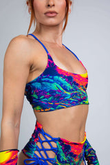 Freedom Rave Wear neon dinosaur sunset print bralette and high-waisted shorts with blue lace-up sides. Bold, vibrant, and perfect for rave events.