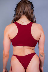 Rear view of a model in a sleek red teaser top and matching bottoms from Freedom Rave Wear, showing a minimalistic style