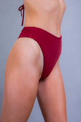 Side view of a red high-waisted rave bottom from Freedom Rave Wear, tailored for a sleek festival look.