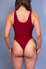 Rear view of a vibrant red Freedom Rave Wear keyhole bodysuit, highlighting its sleek design and snug fit.
