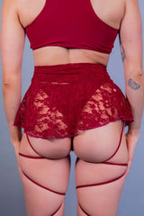 Rear view of a red lace micro skater skirt by Freedom Rave Wear, featuring intricate floral lace and stylish strappy details.