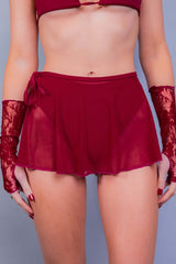 Close-up of a model wearing Freedom Rave Wear's scarlet fantasy red mesh swirl skirt, tied at the side with a bow, paired with matching lace arm cuffs.