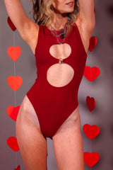 Freedom Rave Wear presents a model in a captivating scarlet bodysuit featuring circular cutouts, complemented by striking jewelry