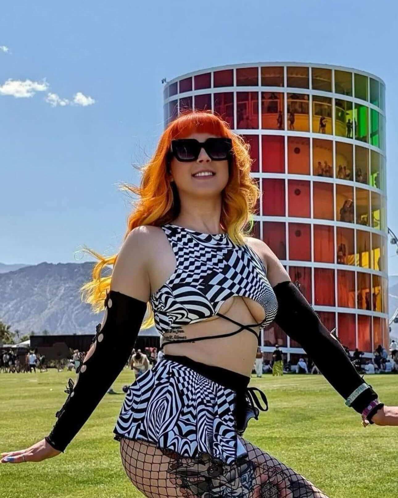 Model wearing a Distortion Swirl Skirt at a festival, showcasing vibrant rave outfits against a colorful backdrop.