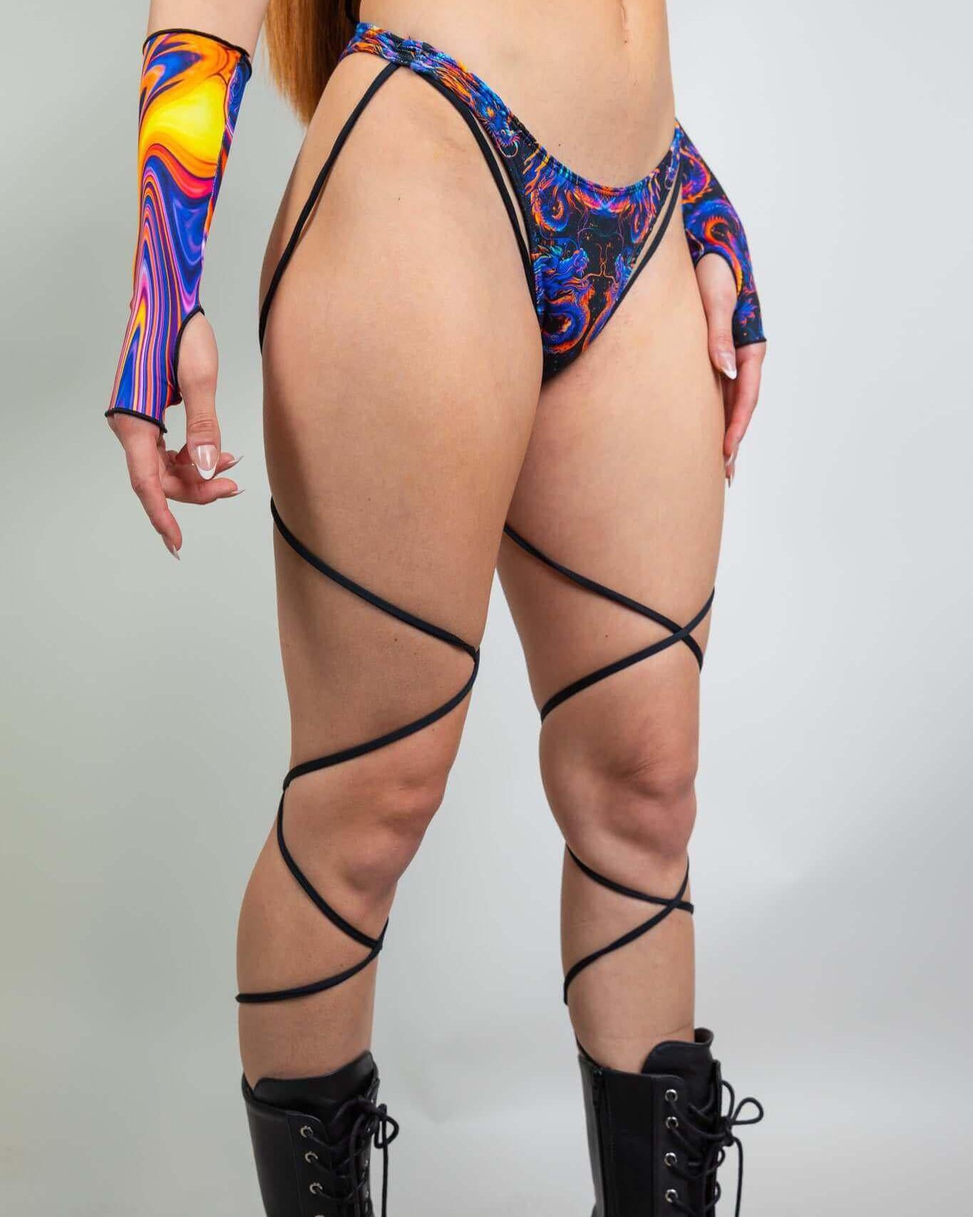 High hip strappy rave bottoms with blue and orange dragon print, featuring stylish strappy details and bold accessories.