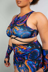 Model wearing ShadowFlame Teaser Top, a colorful cropped rave outfit with dragon design and criss-cross straps.