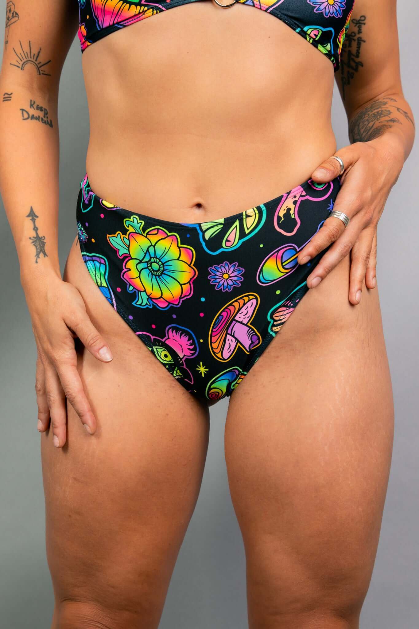 Close-up of Freedom Rave Wear high-waisted rave bottoms showcasing psychedelic floral and mushroom patterns. Paired with matching top.