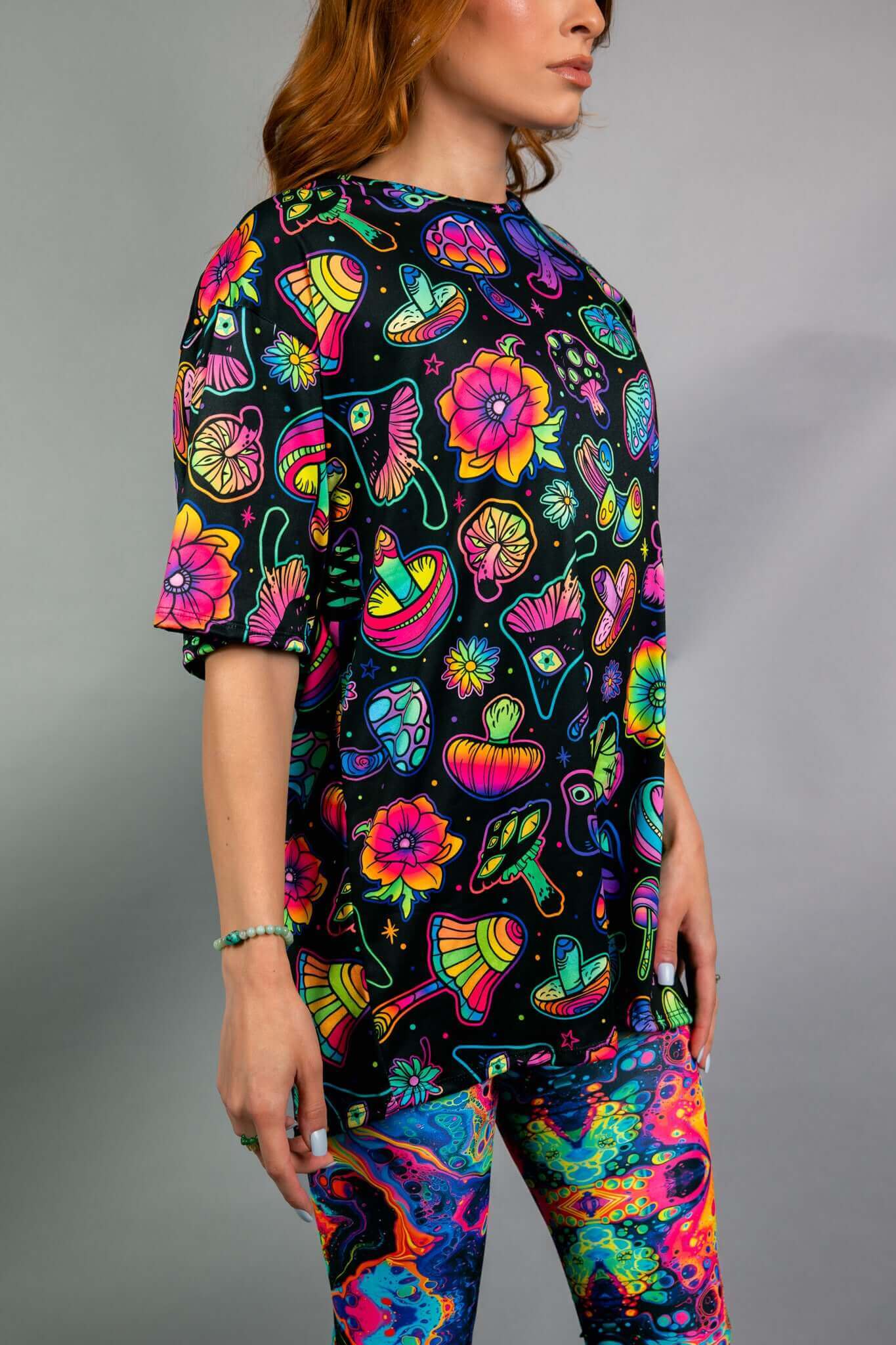  Side view of the vibrant psychedelic oversized tee by Freedom Rave Wear. Bold mushroom and floral patterns make it a rave essential.