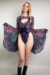 Freedom Rave Wear model in a striking neon floral bodysuit with sheer sleeves and a keyhole cutout, exuding elegance.
