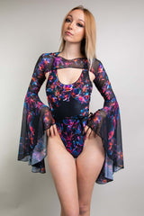 Model in Freedom Rave Wear floral psychedelic print rave bodysuit with dramatic bell sleeves and temptation bodysuit, striking a confident pose.