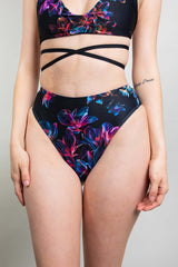 Freedom Rave Wear model in black high-waisted rave bottoms adorned with a vibrant, colorful neon floral pattern and sleek design.