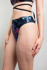 Freedom Rave Wear model in black high-waisted rave bottoms adorned with a vibrant, colorful neon floral pattern and sleek design.