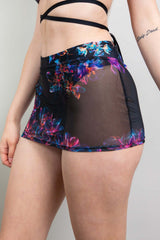 Back view Side view of Model in a Freedom Rave Wear outfit, featuring a criss-cross strapped top and sheer floral print mini skirt, showcasing design details