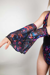 Detail of a model's arm extended in a Freedom Rave Wear rave bodysuit, emphasizing the mesh flare sleeves adorned with a vivid floral print.
