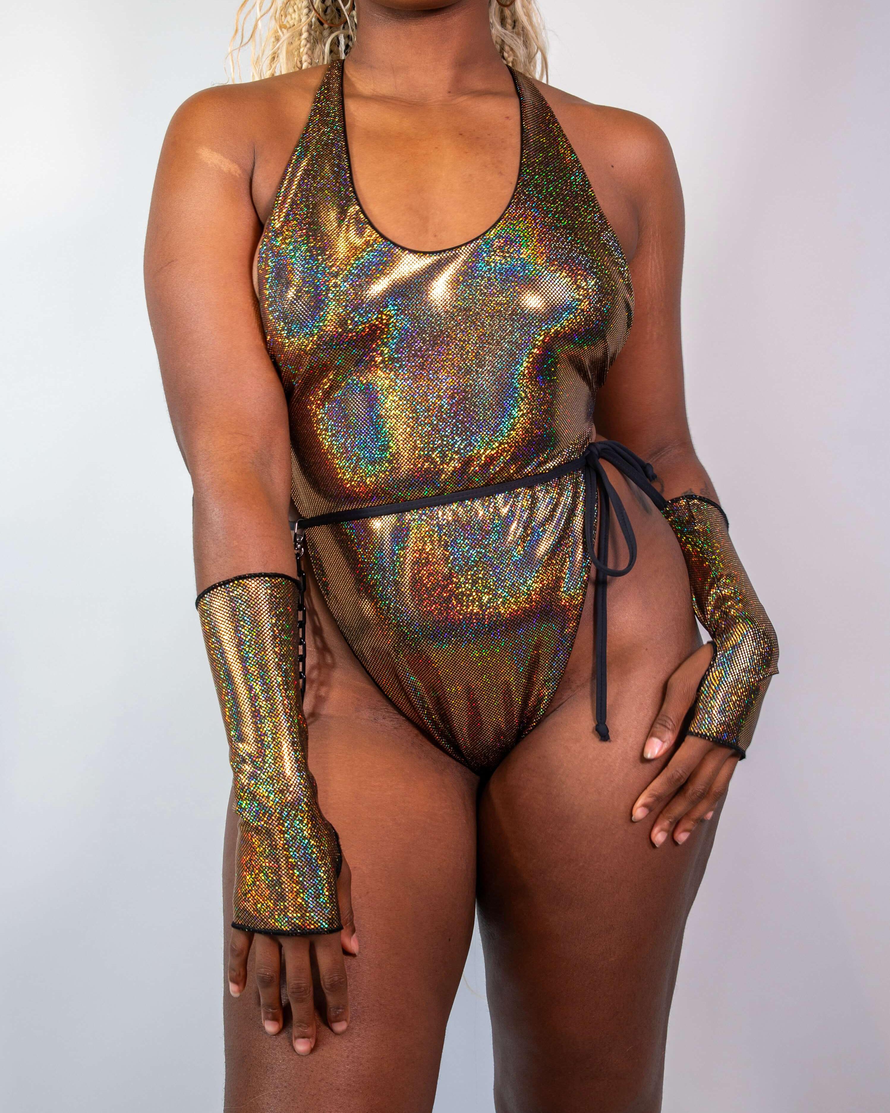 Woman modeling the Starfire Temptation Cheeky One Piece swimsuit, featuring shimmering gold fabric and stylish long ties.