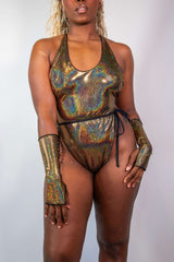 Woman modeling the Starfire Temptation Cheeky One Piece swimsuit, featuring shimmering gold fabric and stylish long ties.