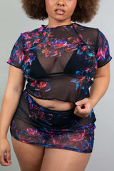 Confident Freedom Rave Wear model in a sheer black rave top and skirt with vibrant neon floral designs, exuding bold style.
