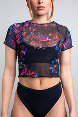 Freedom Rave Wear model showcasing a mesh black rave top with vivid neon floral accents, styled for a sleek look.