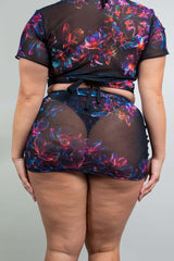 Rear view of a model in a Freedom Rave Wear sheer crop top and mini skirt with a bold floral design, highlighting the tie-up detail at the back.
