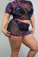 Back view Side view of Model in a Freedom Rave Wear outfit, featuring a criss-cross strapped top and sheer floral print mini skirt, showcasing design details