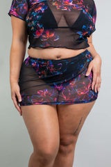 Detailed view of a model in a Freedom Rave Wear sheer crop top and matching floral print mini skirt, highlighting the outfit's layers and textures.