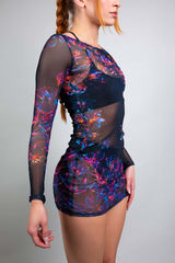Side view of a model in a Freedom Rave Wear floral mesh dress, showcasing the sheer sleeves and vibrant design against a neutral background.