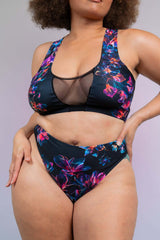 Close-up of a model in a Freedom Rave Wear two-piece swimsuit with floral print and mesh details, posing confidently against a soft background.