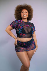 Joyful Freedom Rave Wear model in a black mesh rave top with neon floral prints and matching high-waist skirt.
