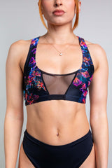 Close-up of a model in a Freedom Rave Wear floral two-piece swimsuit with mesh panel details, showcasing the vibrant design and fit.
