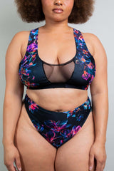 Close-up of a model in a Freedom Rave Wear floral two-piece swimsuit with mesh panel details, showcasing the vibrant design and fit.