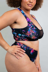 Close-up of a model wearing a Freedom Rave Wear two-piece floral swimsuit with mesh detailing, highlighting the intricate print and design.