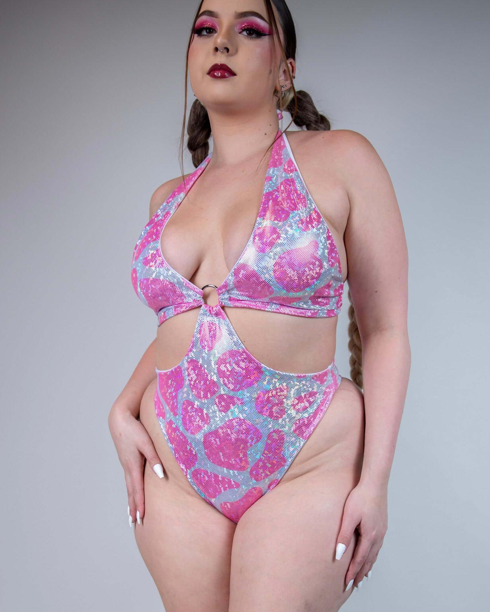 Stylish model showcasing a sparkly pink cow print bodysuit with O-ring detail, perfect for rave outfits.