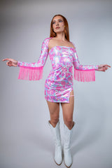 Model showcasing a sparkly pink fringe dress ideal for rave outfits, styled with white boots against a light background.