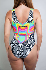 Model wearing a Technicolor Extra Coverage Sideboob Bodysuit, back view featuring colorful geometric pattern and full-coverage design, perfect for rave fashion.