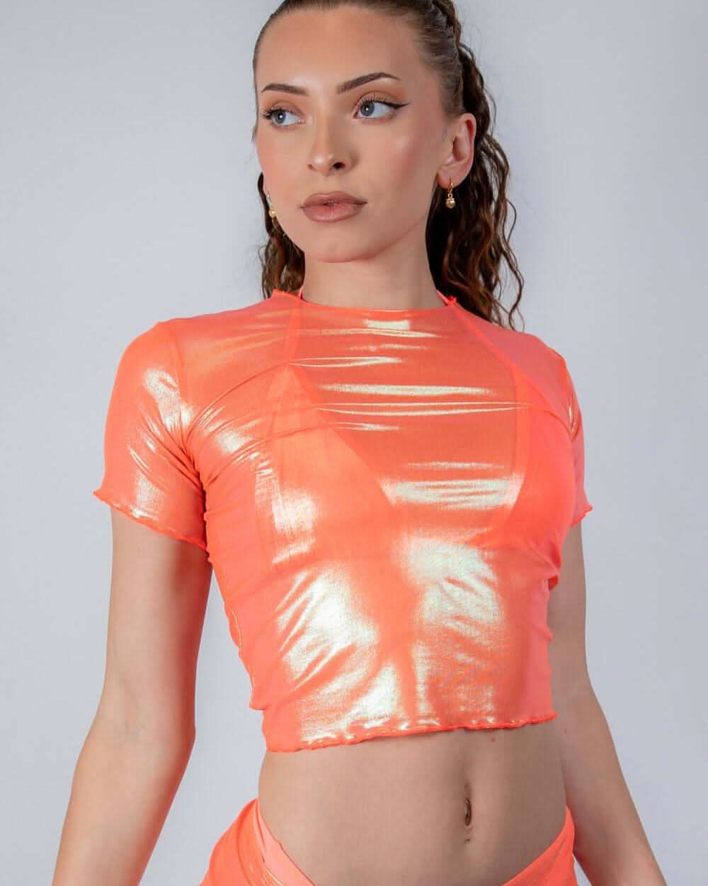 Model wearing a holographic orange mesh baby tee, showcasing a sleek design perfect for rave outfits.