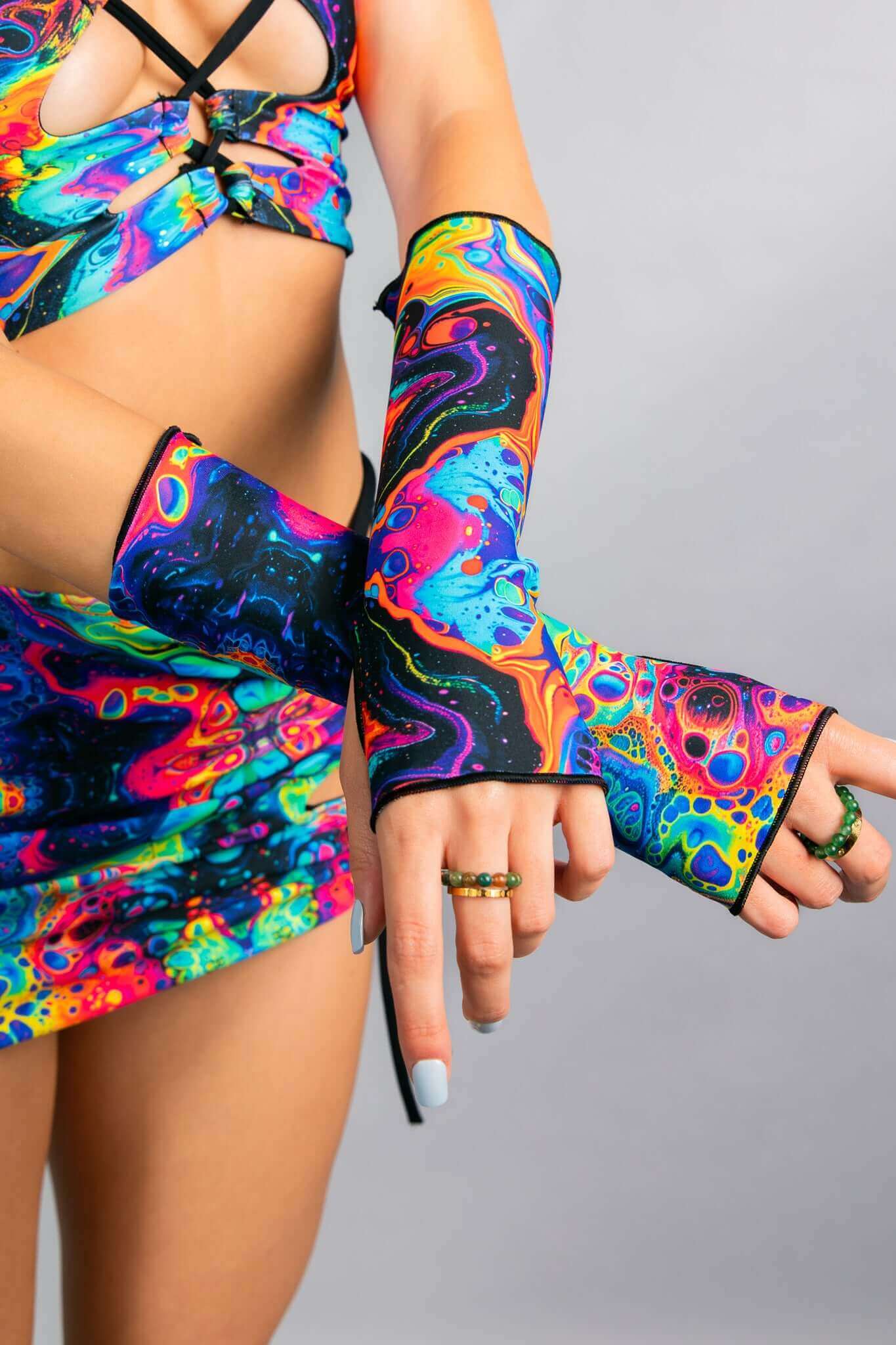 Close-up of model wearing a psychedelic crop top and matching arm sleeves by Freedom Rave Wear, showcasing vibrant swirl patterns and halter straps.