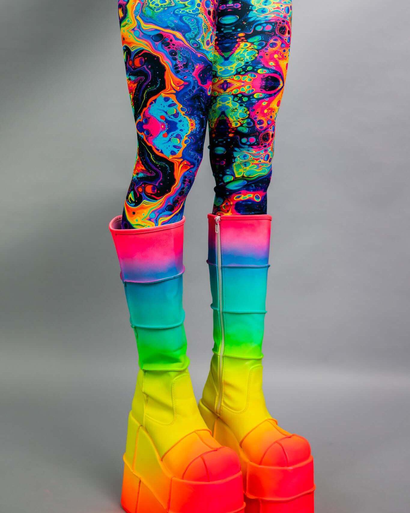 Vivid leg sleeves in colorful psychedelic design paired with vibrant rainbow platform boots, perfect for rave outfits.