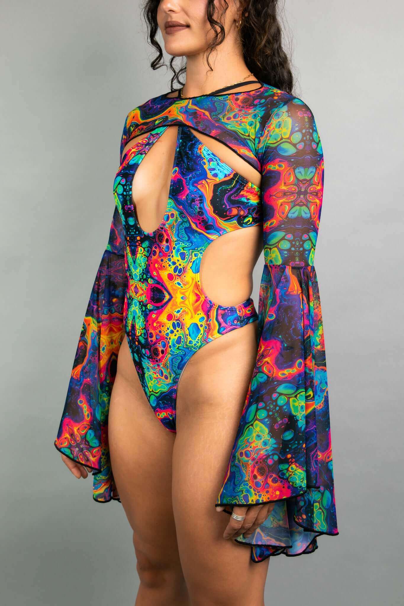 Model shows off Freedom Rave Wear bodysuit with keyhole front, sheer bell sleeves, and vibrant psychedelic design, ideal for festival fashion.