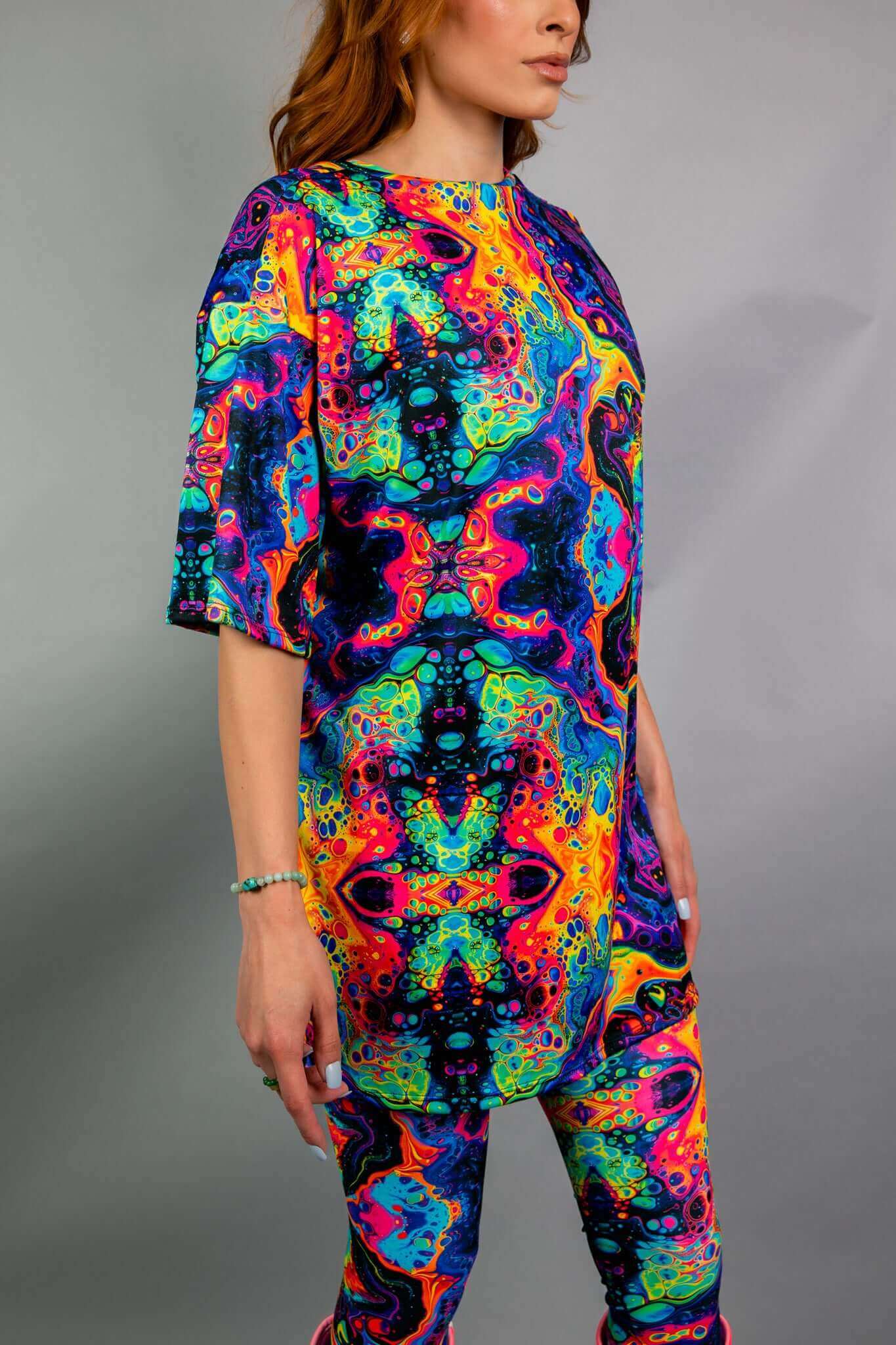 Model showcasing Freedom Rave Wear's trippy psychedelic oversized shirt and leggings, highlighting the bold, vibrant print against a neutral background.