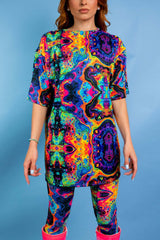 Model wearing Freedom Rave Wear's vibrant psychedelic oversized shirt and matching leggings, set against a blue background.