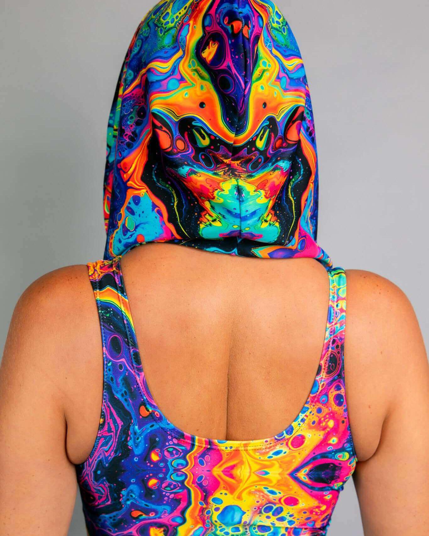 Vibrant rainbow and mushroom print on the Vivid Shroomie! Assassin Hood worn at a rave, showcasing unique style.