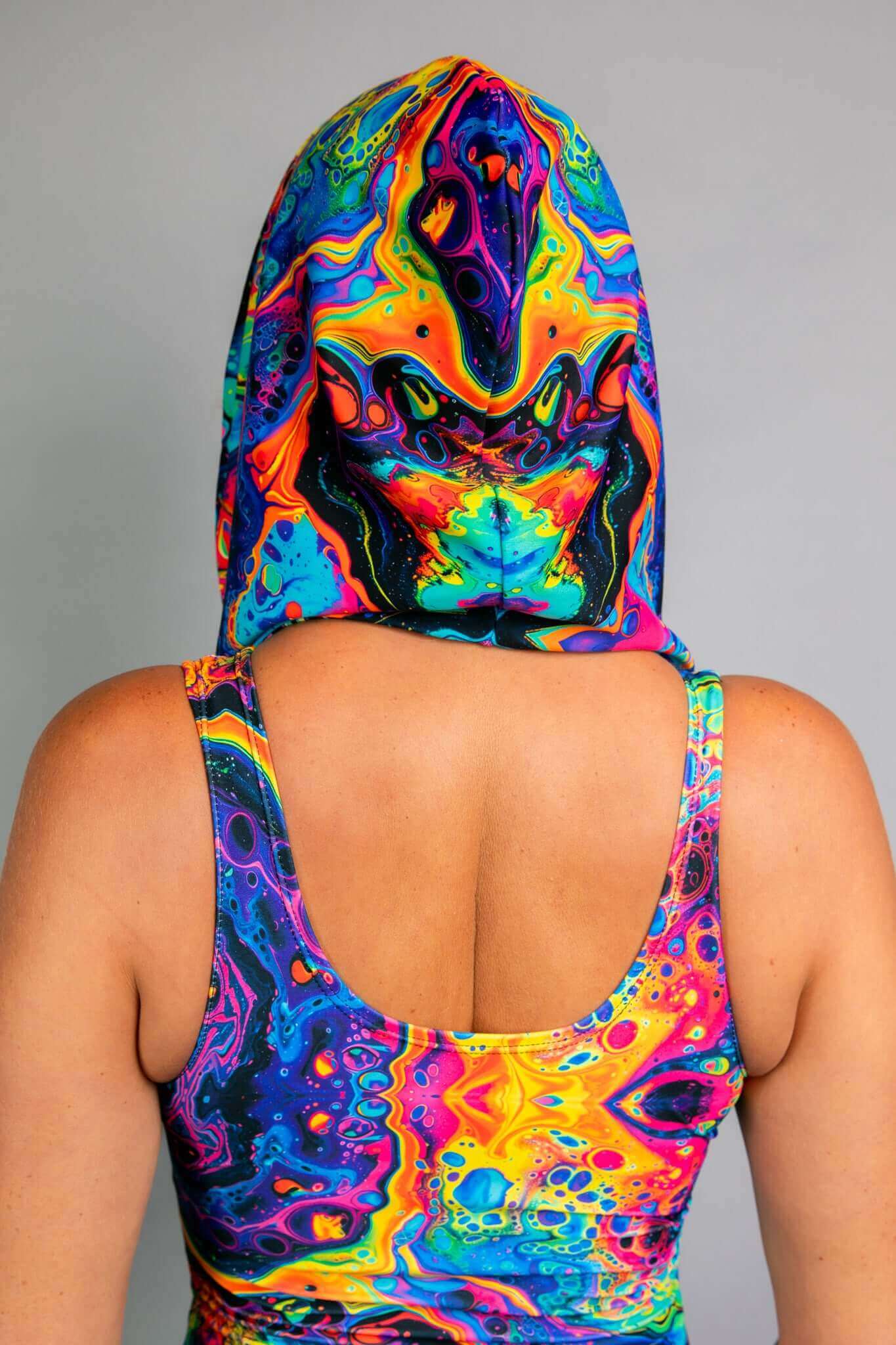 A back view of a Freedom Rave Wear hooded top showcasing a vibrant, swirling psychedelic design in neon colors, paired with a matching scoop-back bodysuit.