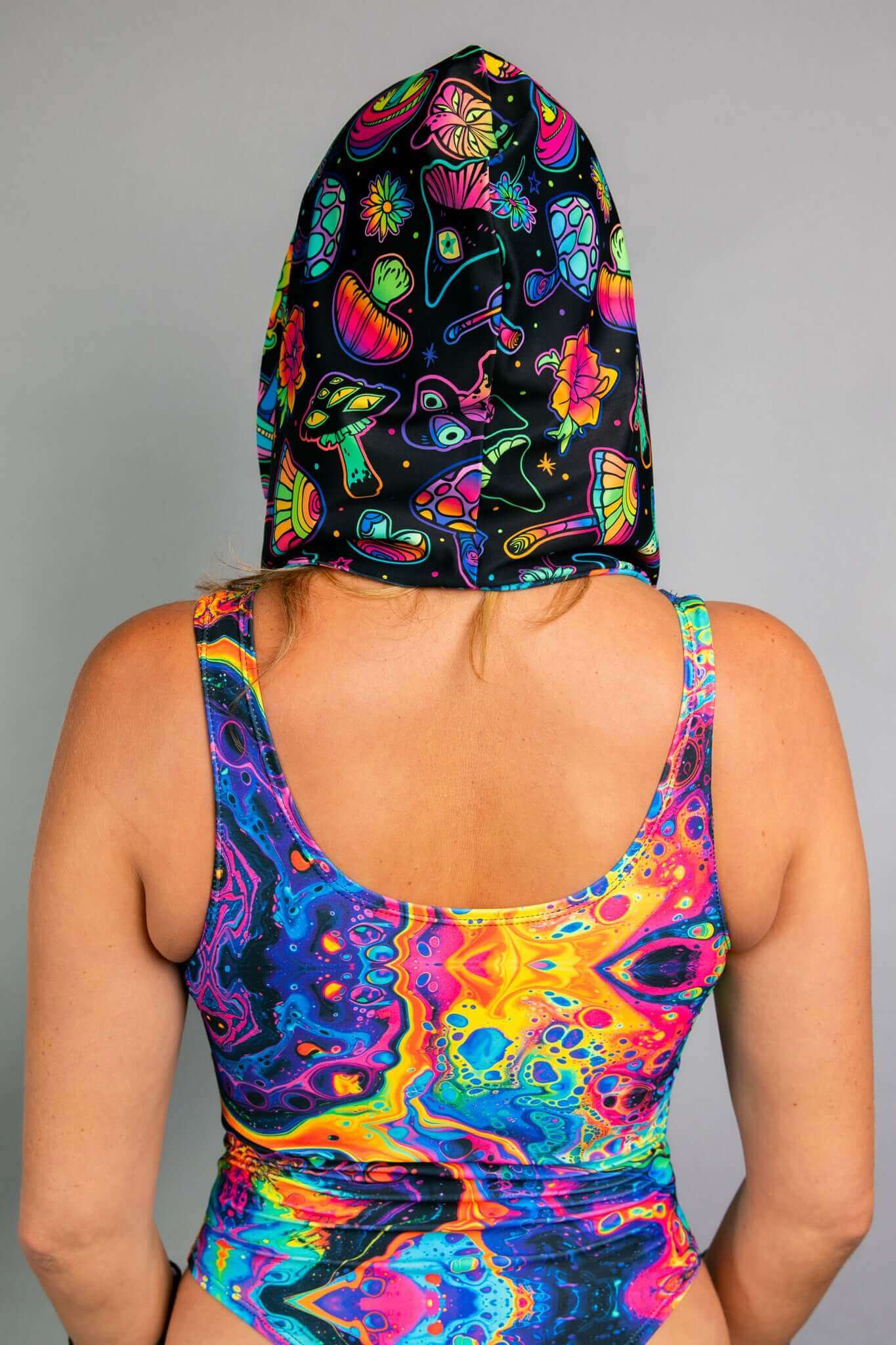  A back view of a Freedom Rave Wear hooded top featuring colorful, neon mushroom and floral patterns, paired with a matching psychedelic bodysuit.